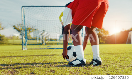 Playing, soccer and preparing for kick, children and player with skills for game, talent and cardio. Outdoor, football and kids with sportswear for match, growth and development of youth or fitness 126407820