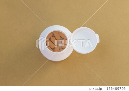 Pills in white open bottle on the yellow nature background. Farmacy concept. Top view. Space for text. Pills in white open bottle on the yellow nature background. Farmacy concept. Top view. Space for text. 126409793