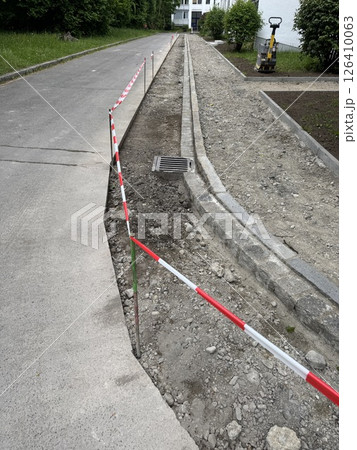 Road is being repaired and a red and white striped barrier is in place 126410063