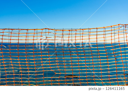 Volleyball net against blue sea water Volleyball net against blue sea water 126411165