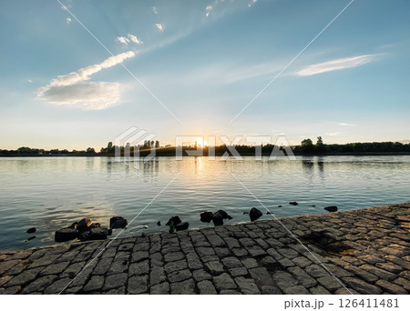 Beautiful sunset over a body of water with a few ducks in the water Beautiful sunset over a body of water with a few ducks in the water 126411481