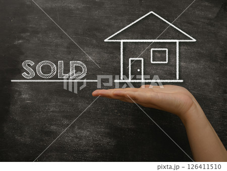 Hand holding a chalkboard with a house and the word sold written on it Hand holding a chalkboard with a house and the word sold written on it 126411510