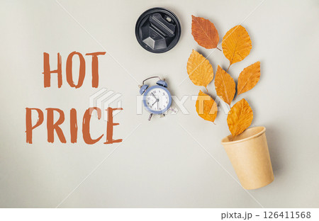 A clock and a cup of leaves are on a table with the words hot price written be A clock and a cup of leaves are on a table with the words hot price written be 126411568