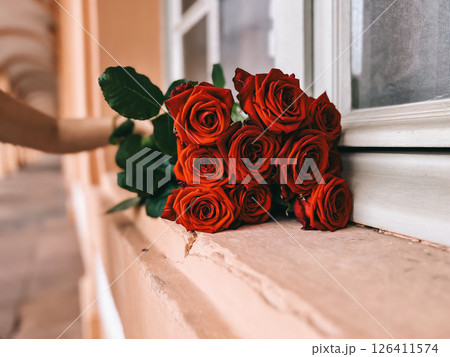 Bouquet of red roses sits on a window sill 126411574