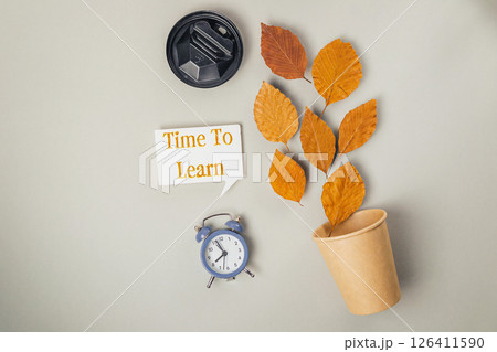 Clock and a cup of coffee are on a table with a leafy plant 126411590