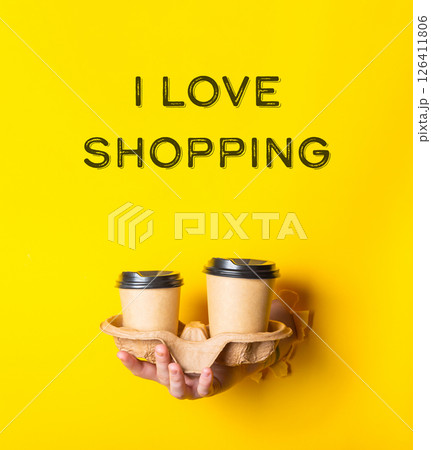A person holding two cups in a paper tray with the words I love shopping writt A person holding two cups in a paper tray with the words I love shopping writt 126411806