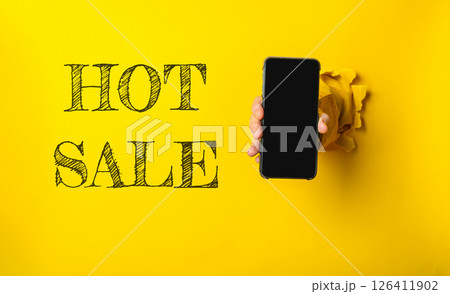A person holding a phone with the word HOT sale written on the wall behind them 126411902