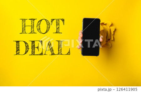 Person holding a phone with the word HOT DEAL written on the wall behind them 126411905