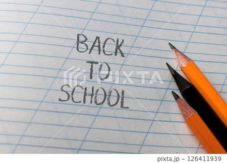 A pencil and two pencils are on a piece of paper with the word back to school A pencil and two pencils are on a piece of paper with the word back to school 126411939