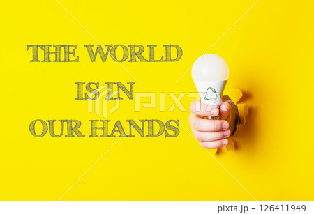 Person holding a light bulb with the words the world is in our hands 126411949