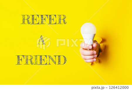 Person holding a light bulb with the words Refer a Friend Person holding a light bulb with the words Refer a Friend 126412000