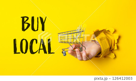 A hand holding a shopping cart with the words Buy Local written below it 126412003
