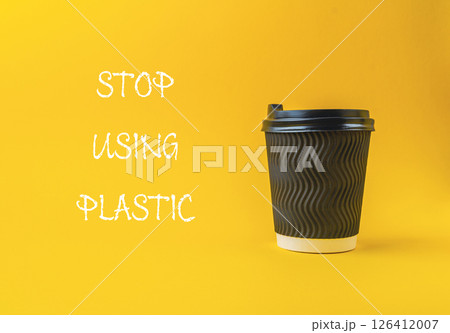 Black coffee cup with a white lid sits on a yellow background 126412007