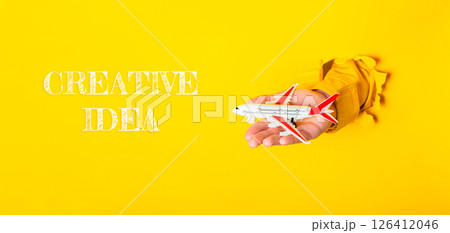 Hand holding a toy airplane with the words Creative Idea written below it 126412046