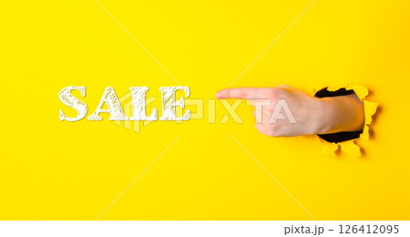 A hand pointing to the word sale on a yellow background A hand pointing to the word sale on a yellow background 126412095