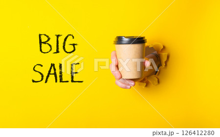 A person is holding a coffee cup with the words Big Sale written on it A person is holding a coffee cup with the words Big Sale written on it 126412280