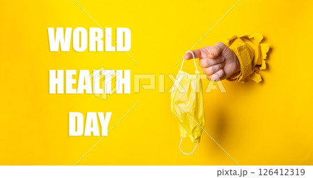 Person holding a yellow mask with the words World Health Day written below 126412319