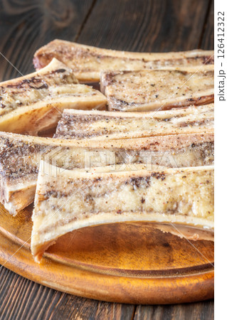 Rustic roasted marrow bones rest on warm wooden board, savory richness revealed Rustic roasted marrow bones rest on warm wooden board, savory richness revealed 126412322