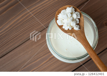 Milk kefir grains on wooden spoon and jar of kefir Milk kefir grains on wooden spoon and jar of kefir 126412401
