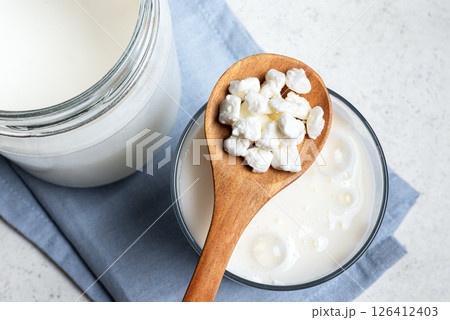 Milk kefir grains on wooden spoon and jar of kefir Milk kefir grains on wooden spoon and jar of kefir 126412403