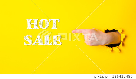 Hand pointing to the word hot sale on a yellow background 126412480