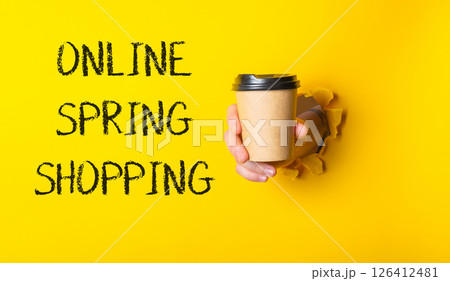 Person holding a coffee cup with the words online spring shopping written in 126412481
