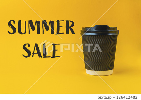 Black coffee cup with a white lid sits on a yellow background 126412482