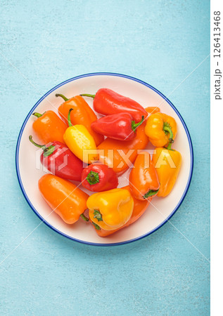 Plate presenting colorful mini bell peppers on blue background 126413468