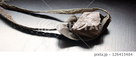 Sling with stone on wooden background 126413484