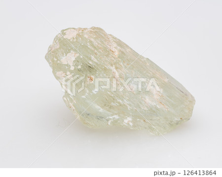 A raw, light green aquamarine crystal, a variety of beryl, showcases its prismatic shape with visible inclusions and a pale, milky hue on a clean white surface mineral specimen 126413864