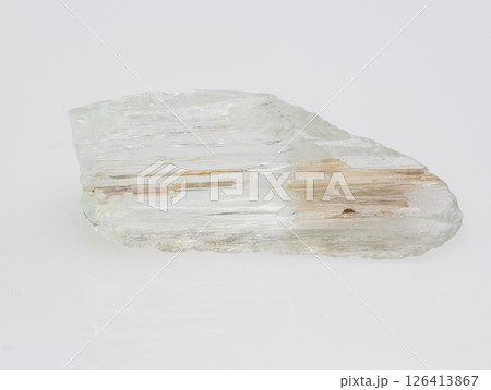 A Roughly Cut Pale Green Beryl Crystal Specimen Exhibiting Schiller Effect, with Visible Inclusions and Parallel Striations, Against a Neutral Light Gray Background A Roughly Cut Pale Green Beryl Crystal Specimen Exhibiting Schiller Effect, with Visible Inclusions and Parallel Striations, Against a Neutral Light Gray Background 126413867