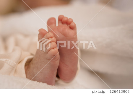 Close-up view of a newborn baby's delicate tiny feet resting on a soft, fluffy white blanket, capturing the innocence and tenderness of new life 126413905