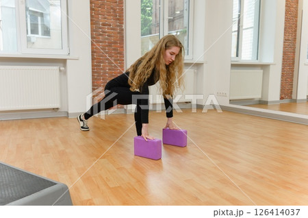 Young woman stretching with yoga blocks indoors. 126414037