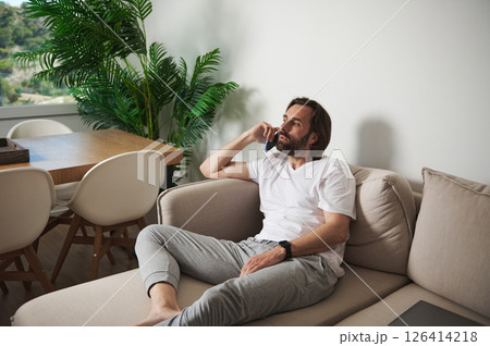 Man Relaxing at Home While Talking on Phone in Minimalist Interior 126414218