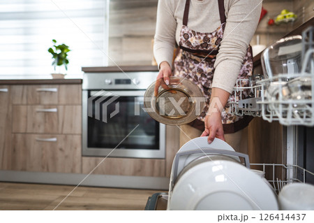 Woman loading the dishwasher in the kitchen Woman loading the dishwasher in the kitchen 126414437