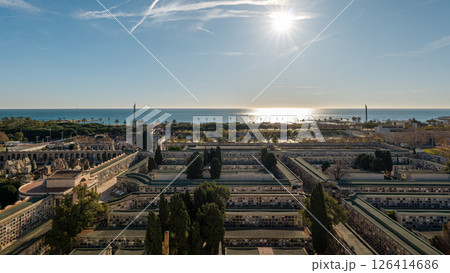 Sunny panoramic view of sea and historic cemetery in Barcelona lined with green trees and palm trees Sunny panoramic view of sea and historic cemetery in Barcelona lined with green trees and palm trees 126414686