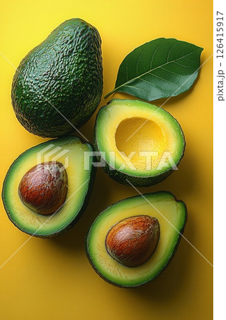 Fresh Avocados with Green Leaves Displayed on a Bright Yellow Background 126415917