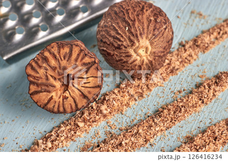 nutmegs and strands of grated mace powder on a blue painted wooden table nutmegs and strands of grated mace powder on a blue painted wooden table 126416234