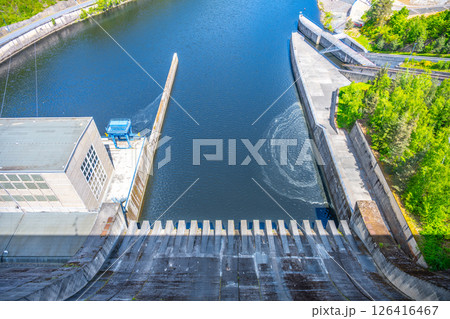 Orlik Dam showcases its impressive structure overlooking flowing water. The installation plays a crucial role in hydroelectric power generation in Czechia, surrounded by lush greenery. Orlik Dam showcases its impressive structure overlooking flowing water. The installation plays a crucial role in hydroelectric power generation in Czechia, surrounded by lush greenery. 126416467