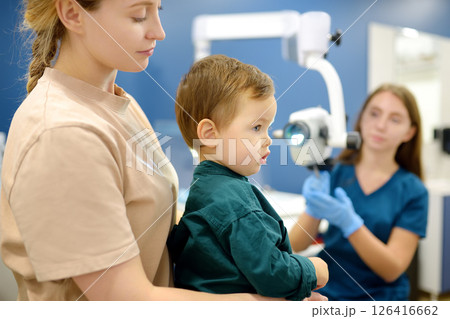 A cute toddler boy with his mother are at an appointment with a pediatric ENT to prepare for kindergarten. A cute toddler boy with his mother are at an appointment with a pediatric ENT to prepare for kindergarten. 126416662
