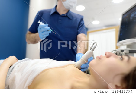 Skillful oncologist puncture of mammary glands of young patient under review ultrasound for diagnosis of breast cancer. 126416774