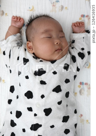 バンザイの格好で寝る生後3ヶ月の女の子の赤ちゃん バンザイの格好で寝る生後3ヶ月の女の子の赤ちゃん 126416935