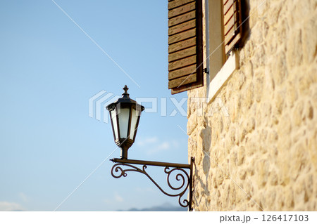 Old lantern on the house wall in Perast, one of the most picturesque towns on the Bay of Kotor. Typical details of an old European coastal town Old lantern on the house wall in Perast, one of the most picturesque towns on the Bay of Kotor. Typical details of an old European coastal town 126417103