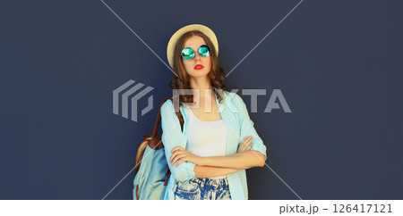 Portrait stylish modern young woman in summer tourist hat with backpack posing on black background Portrait stylish modern young woman in summer tourist hat with backpack posing on black background 126417121