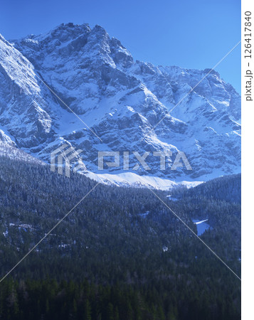 Snow-covered mountains rise majestically under a clear blue sky in winter landscape 126417840