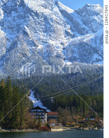 Stunning winter landscape featuring snow-capped mountains and a scenic lake beneath a clear blue sky Stunning winter landscape featuring snow-capped mountains and a scenic lake beneath a clear blue sky 126417845