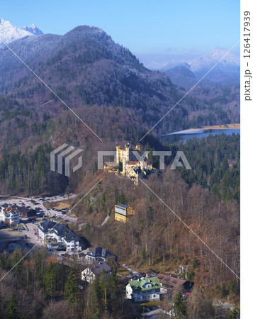Stunning aerial view of Neuschwanstein Castle surrounded by majestic mountains and a tranquil lake on a clear day 126417939