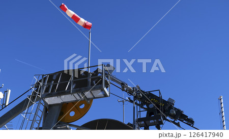 Wind sock indicates wind direction at an industrial site during a clear day in the afternoon Wind sock indicates wind direction at an industrial site during a clear day in the afternoon 126417940