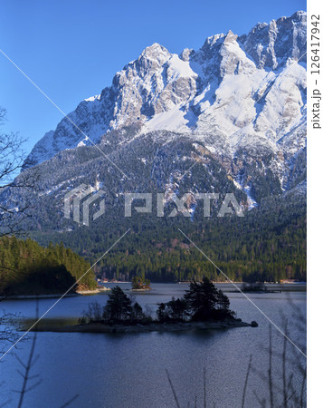 Majestic snow-capped mountains surround a tranquil lake under a clear blue sky in the afternoon Majestic snow-capped mountains surround a tranquil lake under a clear blue sky in the afternoon 126417942