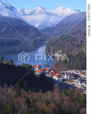 Mountain village nestled by a serene lake surrounded by snow-capped peaks in winter sunlight Mountain village nestled by a serene lake surrounded by snow-capped peaks in winter sunlight 126417984